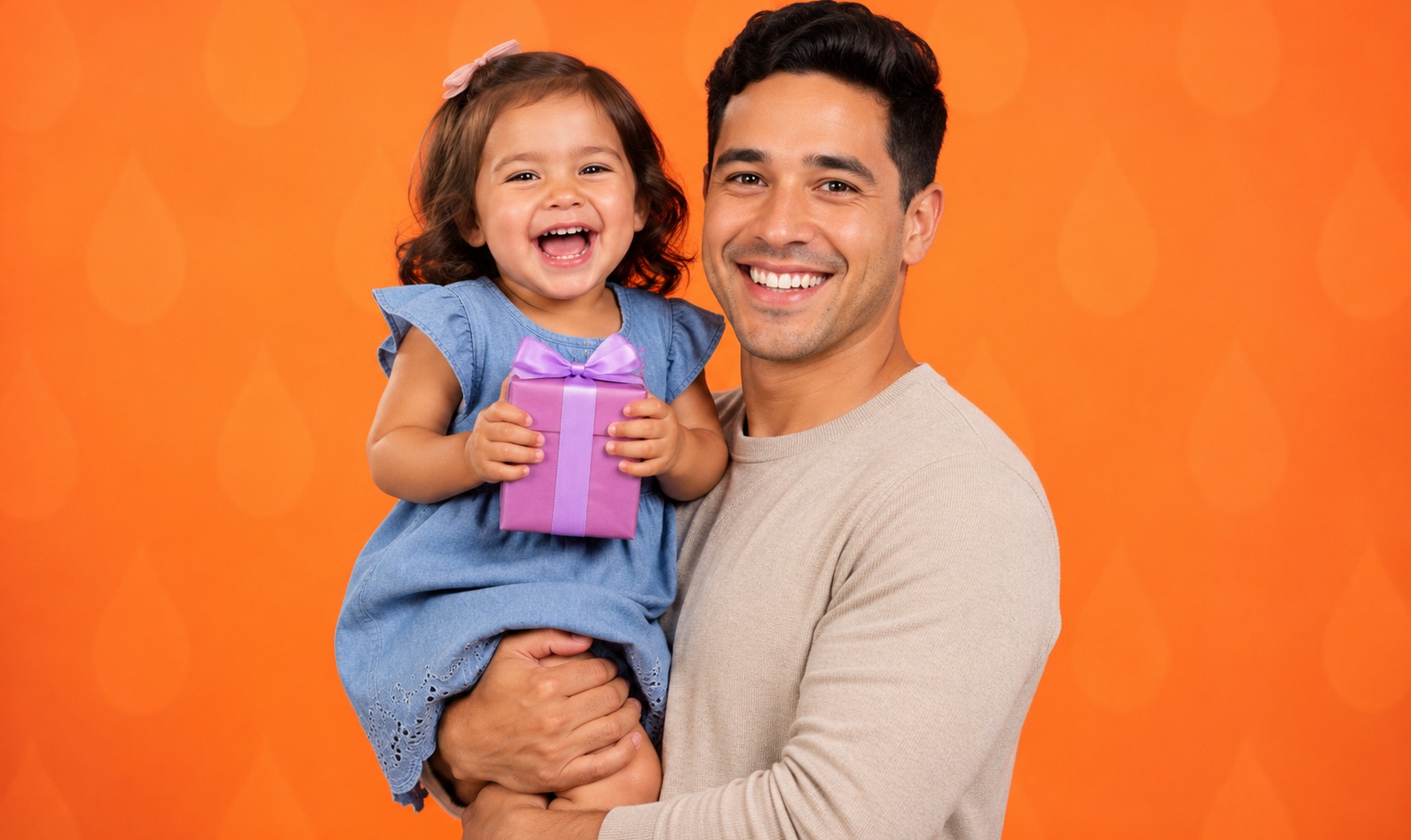 A father holding a toddler who is holding a small wrapped gift